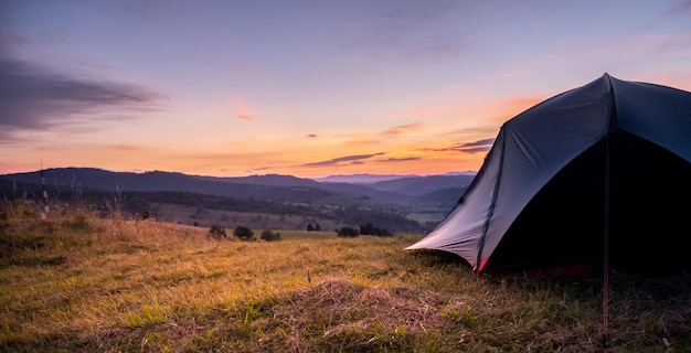 Tenda turistica in montagna sotto il drammatico cielo serale Tramonto colorato in montagna Concetto di viaggio in campeggio Viaggiatori che si godono la vacanza alternativa di vantaggio