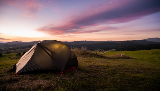 Tenda turistica in montagna sotto il drammatico cielo serale Tramonto colorato in montagna Concetto di viaggio in campeggio Viaggiatori che si godono la vacanza alternativa di vantaggio