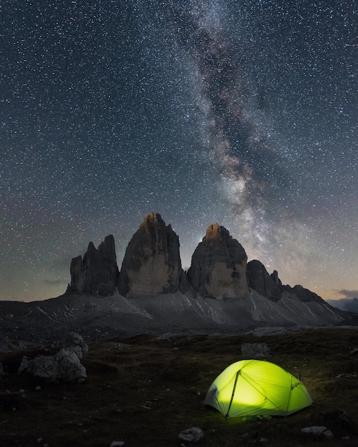 Tenda verde illuminata dall'interno sullo sfondo di un incredibile cielo stellato