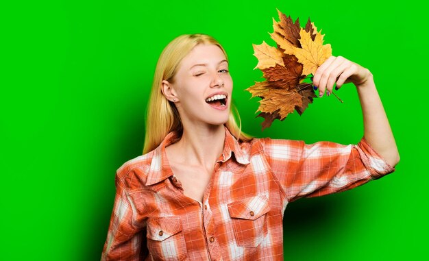 Tendenza moda per l'autunno bellissima ragazza con l'occhiolino in camicia a quadri con foglie autunnali, modella bionda con