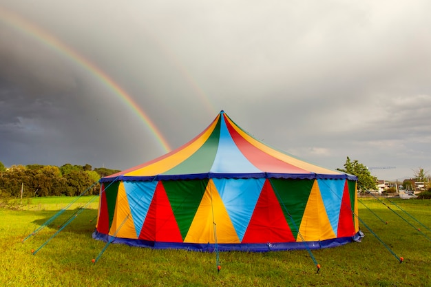 Tendone da circo colorato in una giornata piovosa con un arcobaleno nel cielo