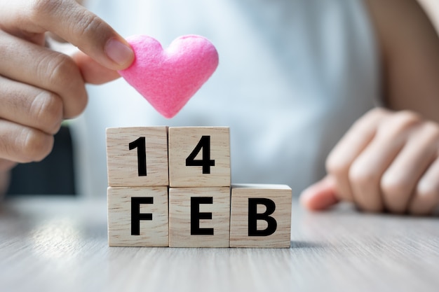 tenendo a forma di cuore rosa con cubo di legno