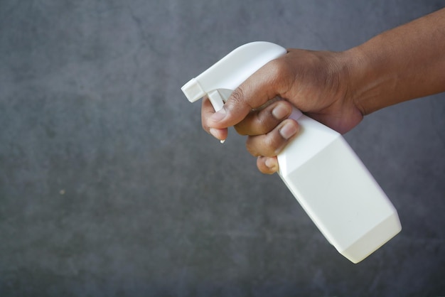 tenendo il flacone spray di colore bianco con spazio per la copia su sfondo nero