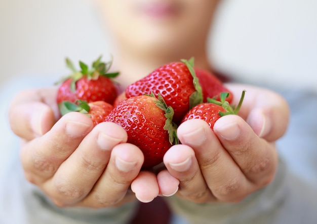 Tenendo la fragola fresca nelle mani