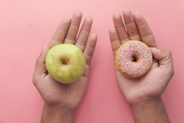 Tenendo la frutta mela e ciambella scegliere il concetto di cibo sano