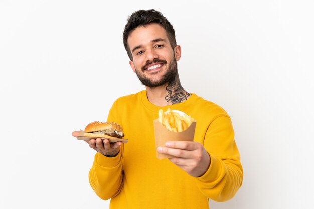 Tenendo patatine fritte e cheeseburger su sfondo isolato