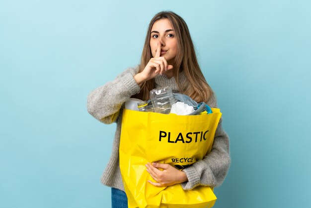 Tenendo una borsa piena di bottiglie di plastica per riciclare il gesto di silenzio facendo blu isolato