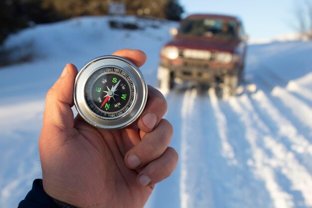 Tenendo una bussola sullo sfondo di un'auto in inverno