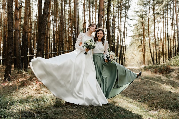 Tenera sposa con damigelle sorridenti vestite con lunghi abiti eleganti, damigelle con sposa felice il giorno delle nozze. i bouquet da sposa sono tenuti da fidanzate, il giorno del matrimonio,