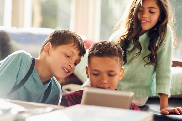 Tenere i bambini occupati con la tecnologia Foto di bambini piccoli che usano una tavoletta digitale insieme a casa