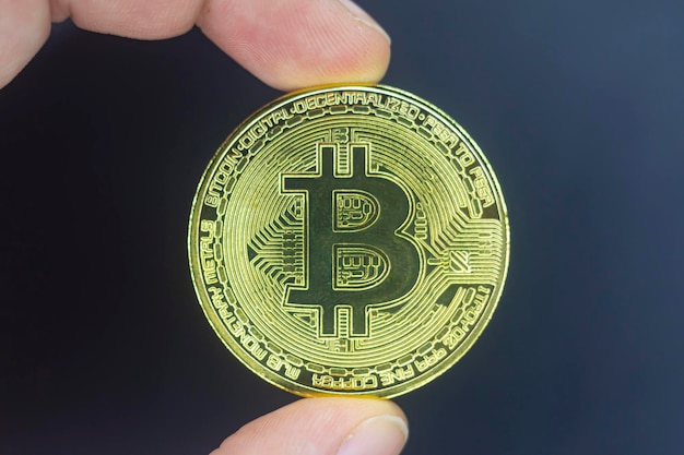 Tenere il dito bitcoin dorato su nero isolato Tenere in mano l'oro bitcoin crypto ditital concetto di denaro