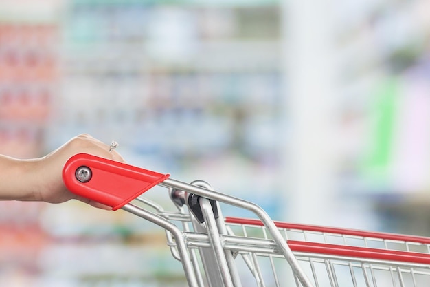 Tenere in mano il carrello rosso vuoto con sfondo sfocato farmacia farmacia