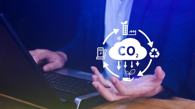 Tenere in mano l'icona virtuale di riduzione della CO2 per ridurre le emissioni di anidride carbonica, l'impronta di carbonio e il credito di carbonio per limitare il riscaldamento globale dal concetto di cambiamento climatico Bio