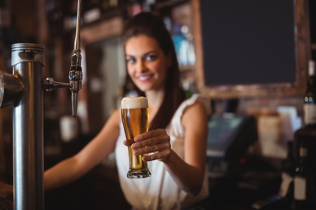 Tenero bar femminile che tiene un bicchiere di birra