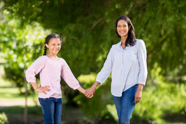 Tenersi per mano di sua figlia in parco della madre