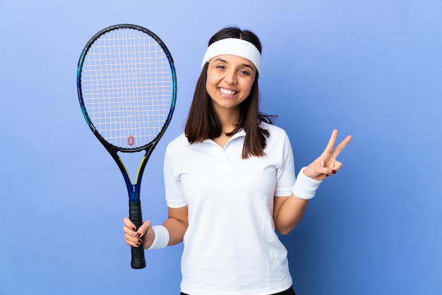 Tennis della giovane donna sopra isolato mostrando il segno di vittoria con entrambe le mani