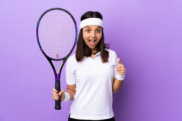Tennis della giovane donna sopra la parete che mostra segno e pollice giusti sul gesto