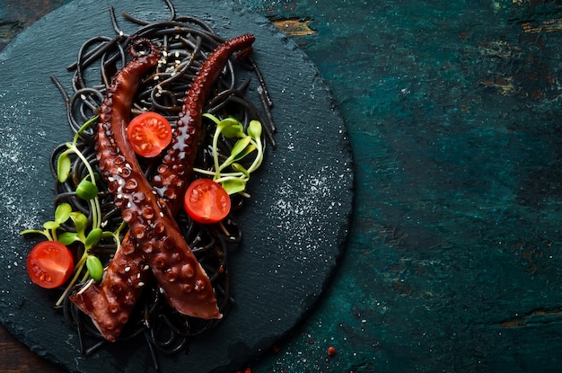 Tentacoli di polpo cotti in salsa all'aglio e pasta nera al nero di seppia Cibo da ristorante di lusso Frutti di mare Stile rustico Piatto Lay