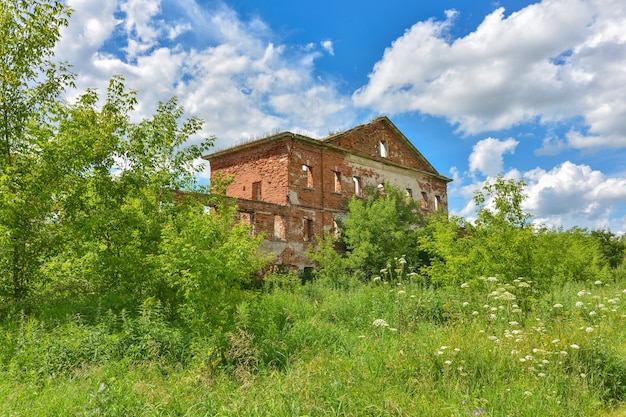 Tenuta di mattoni rossi abbandonata circondata dal verde sullo sfondo del cielo