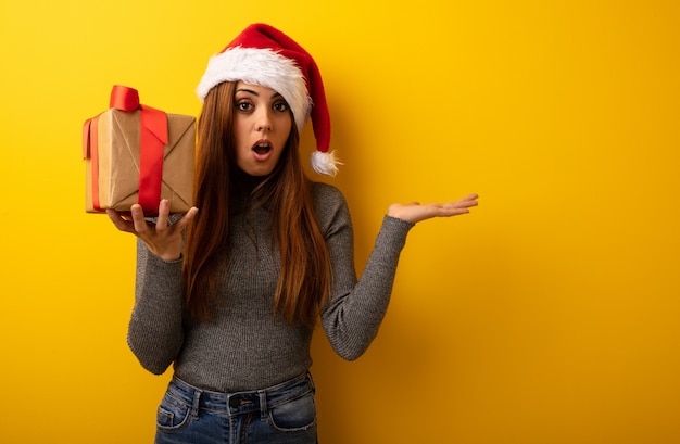 Tenuta graziosa del regalo della tenuta della giovane donna qualcosa sulla mano della palma