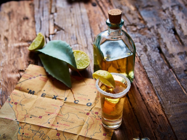 Tequila con calce e sale marino su tavolo di legno a fuoco selettivo