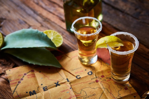 Tequila con calce e sale marino su tavolo di legno a fuoco selettivo