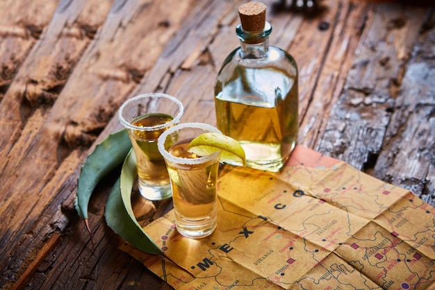Tequila con calce e sale marino su tavolo di legno a fuoco selettivo