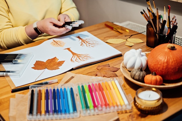 Terapia artistica per il recupero della salute mentale Fare arte aiuta a migliorare la salute mentale Creatività e recupero Ritratto senza volto di una donna che disegna alberi autunnali con pennarelli