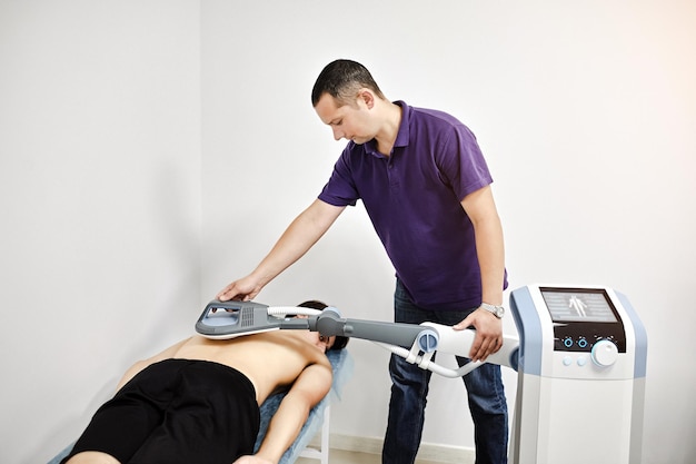 Terapia elettromagnetica della schiena Il medico fisioterapista utilizza apparecchiature mediche per un trattamento altamente efficace del dolore e dell'infiammazione Schiena La riabilitazione del campo magnetico Magnetoterapia