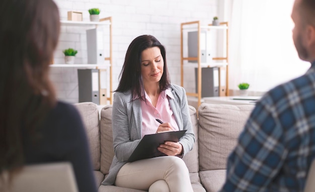 Terapia familiare. Psicologo professionista che prende appunti all'incontro di coppia con i pazienti