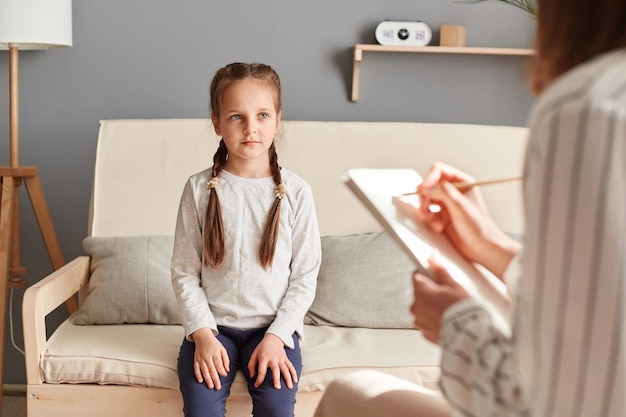 Terapia mentale per bambini Psicologa donna professionista che lavora con la bambina in ufficio specialista che prende appunti sulla condizione della ragazza su carta