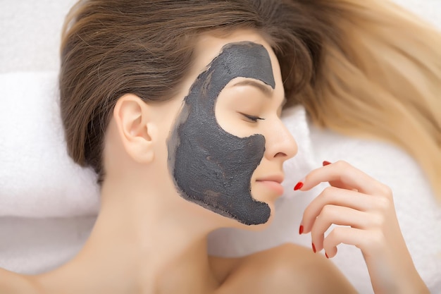 Terapia termale per giovane donna con maschera facciale al salone di bellezza al chiuso