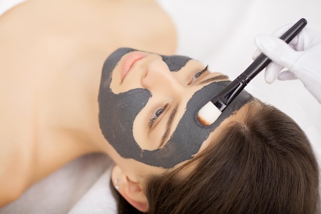 Terapia termale per giovane donna con maschera facciale al salone di bellezza