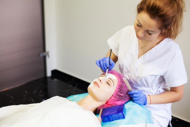 Terapia termale per giovane donna con maschera facciale al salone di bellezza