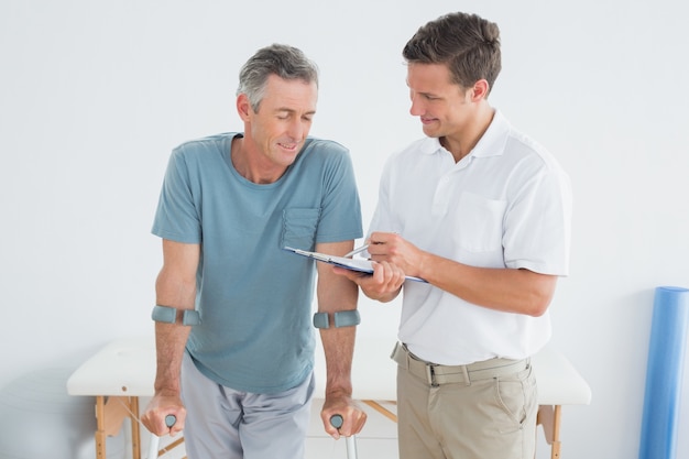 Terapista che discute i rapporti con il paziente disabile in palestra