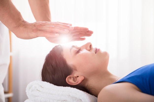 Terapista che esegue il trattamento di guarigione Reiki sulla donna