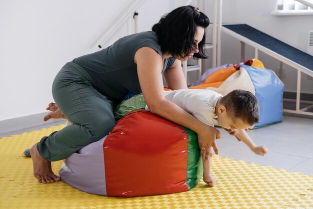 Terapista che fa esercizi sul materassino con bambino disabile