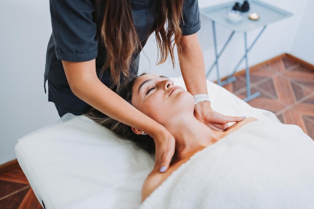 Terapista femminile che fa un massaggio al collo e alle spalle per una paziente stressata a faccia in su Rilassante