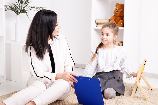 Terapista femminile che lavora con un bambino con problemi di pronuncia nell'armadio bianco.