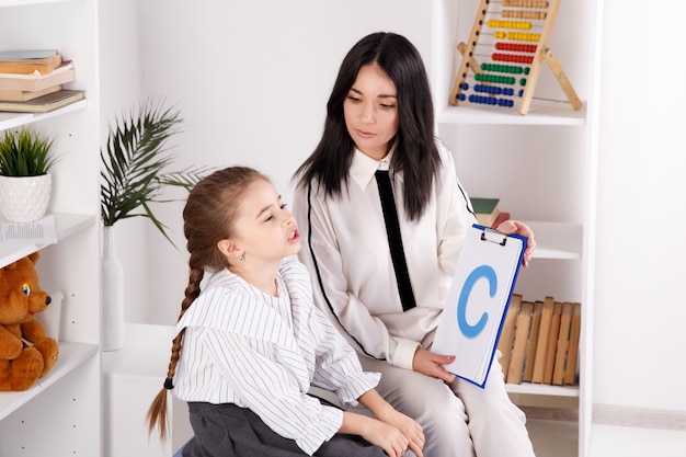 Terapista femminile che lavora con un bambino con problemi di pronuncia nell'armadio bianco.