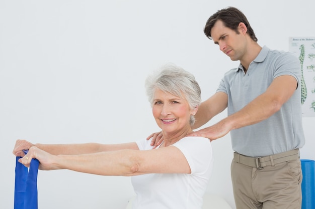 Terapista maschio che assiste donna senior con esercizi