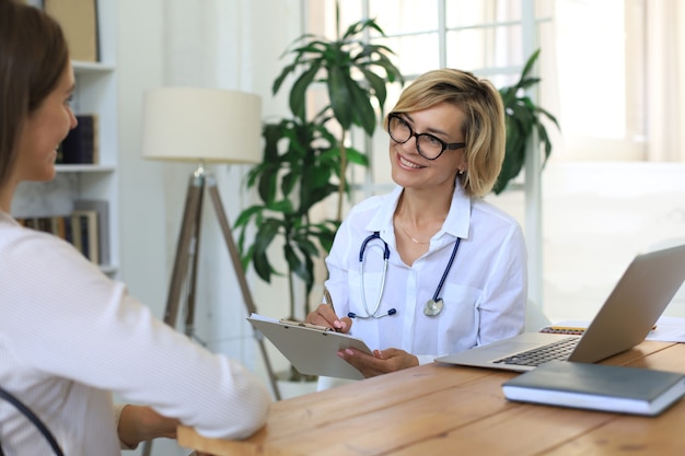 Terapista medico femminile di mezza età in consultazione con il paziente in ufficio.