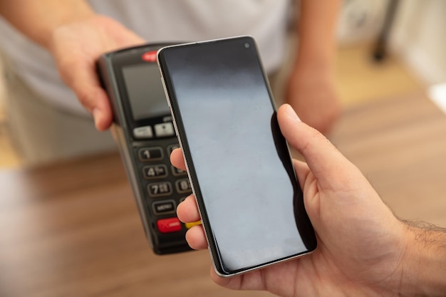 Terminale POS per pagamento con tecnologia smartphone nfc Cassiere e mani cliente