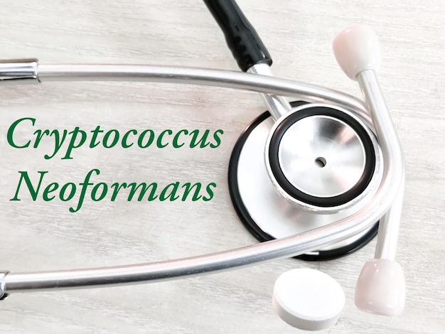 Termine medico di Cryptococcus Neoformans su fondo di legno con stetoscopio e droghe