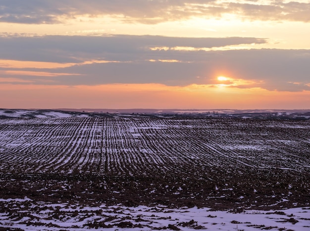 Terra arabile nera coperta dall'ultima neve all'inizio della primavera Calmo tramonto serale nella campagna ucraina nella regione di Lviv