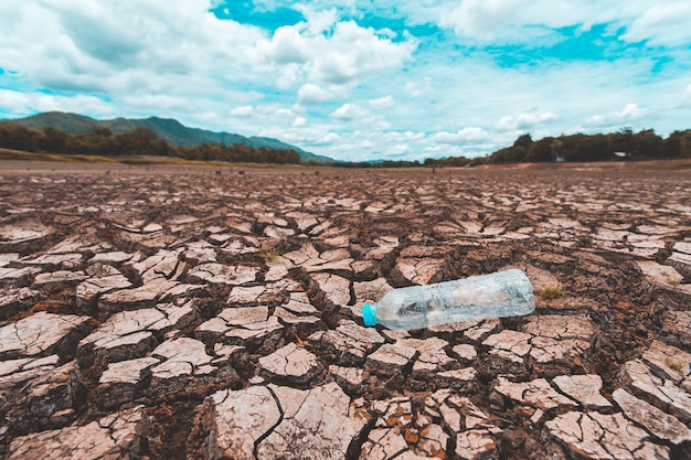 Terra asciutta incrinata con bottiglia di plastica vuota