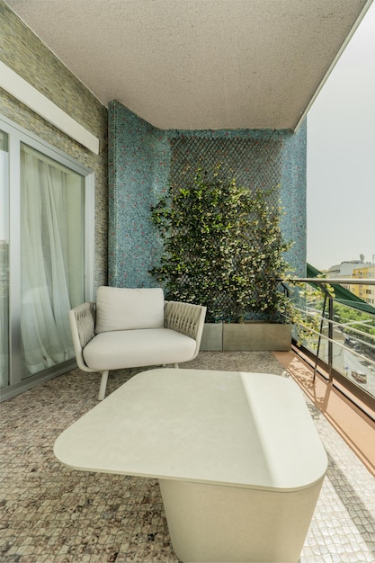 Terrazza con poltrone in tessuto grigio, ringhiera in metallo, giardino verticale su parete blu, tavolino in marmo e vista sulla città