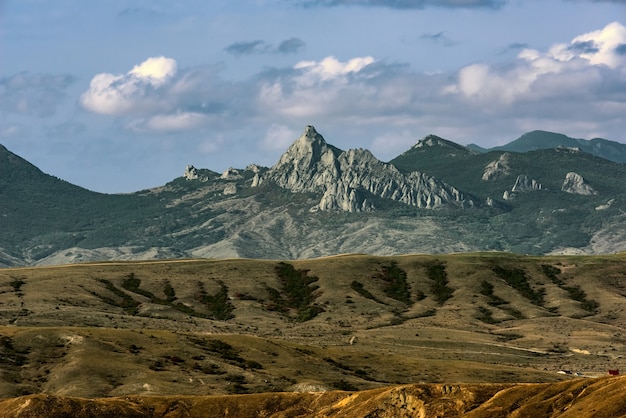 Terreno argilloso con canaloni e burroni senza vegetazione e montagne rocciose all'orizzonte