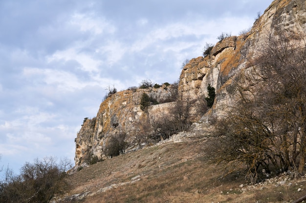 Terreno invernale della Crimea centrale con scogliere rocciose ai margini della cuesta e antiche mura della fortezza tra le rocce