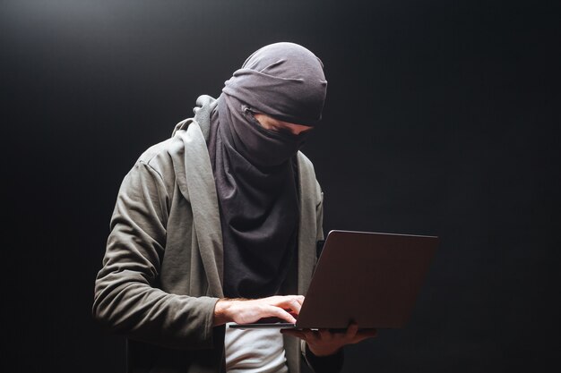 Terrorista con laptop su sfondo nero